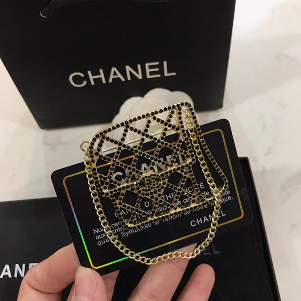 BAG SHAPED BROOCH IN GOLD METAL WITH BLACK CRYSTAL