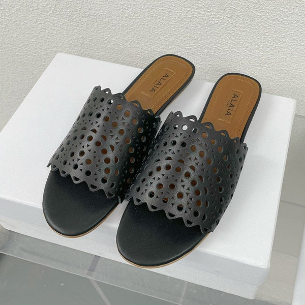 ALAIA VIENNE FLAT MULES IN BLACK LAMBSKIN